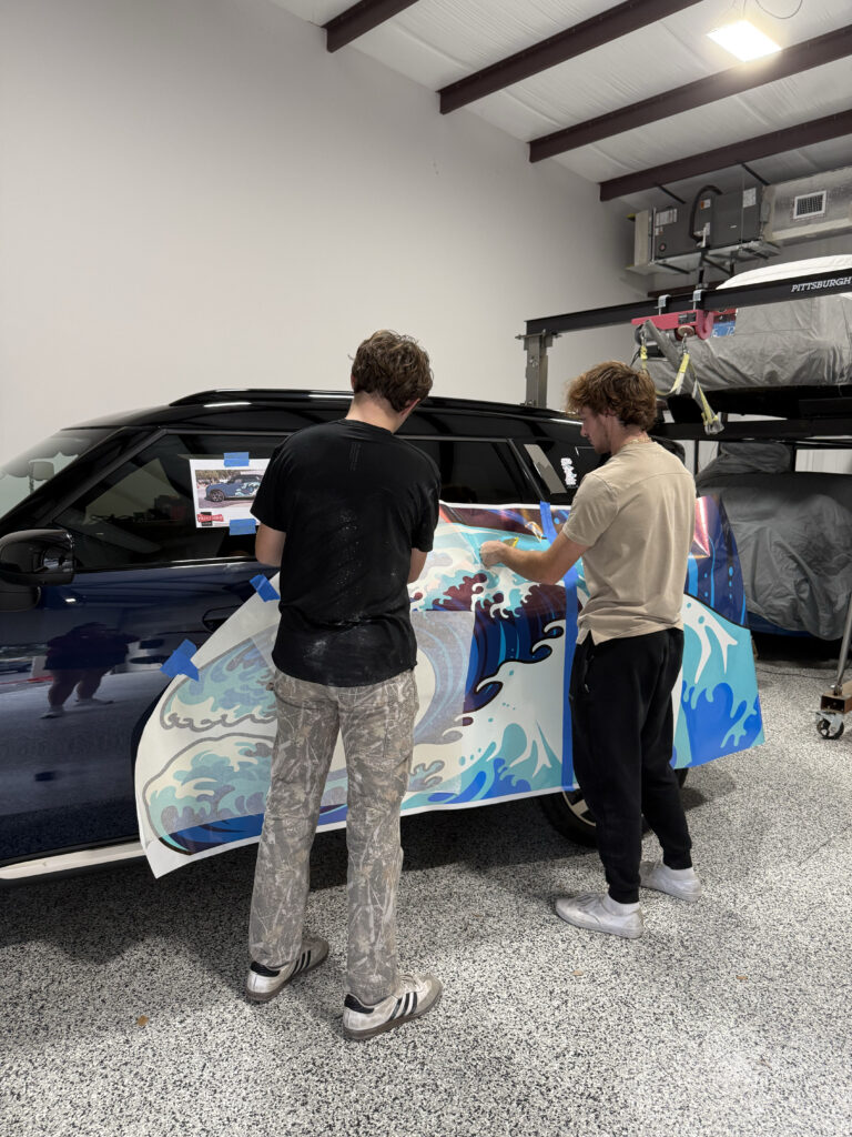 Two men putting sticker on the car